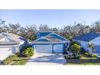 Two-story house with blue siding, two-car garage, and landscaping at 3514 Shimmering Oaks Dr, Parrish, FL 34219
