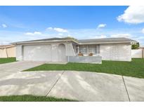 Ranch-style home with a white exterior, attached garage, and well-maintained lawn at 4406 Woodtrail Blvd, New Port Richey, FL 34653