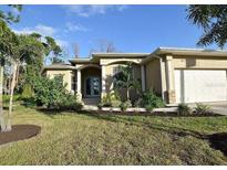 House exterior featuring a tan, two-car garage home with manicured landscaping at 7 Barge Ln, Placida, FL 33946