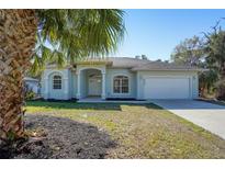 Single-story home with light blue exterior, attached garage, and palm trees at 2559 Comet Ln, North Port, FL 34286