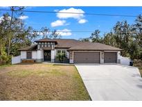 Single-story home with three-car garage and landscaped yard at 3260 Wentworth St, North Port, FL 34288