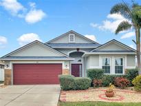 Attractive one-story home with a red garage door and landscaped yard at 407 Stone Briar Dr, Ruskin, FL 33570