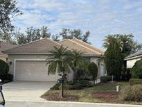 Tan single-story house with a two-car garage and palm trees at 3375 Osprey Ln, Port Charlotte, FL 33953
