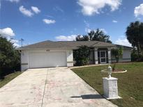 Charming single-story home with a well-maintained lawn, paved driveway, and attached two-car garage at 402 Lomond Dr, Port Charlotte, FL 33953