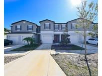 Three-unit townhome building, gray exterior, two-car garages, and landscaping at 11855 Dumaine Valley Rd, Riverview, FL 33579