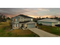 Two-story home with gray and blue exterior, landscaped yard, and attached garage at 25393 Durango Ct, Punta Gorda, FL 33955