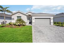 Charming one-story home featuring a well-manicured lawn, elegant brick driveway, and a two-car garage at 11400 Burgundy Dr, Venice, FL 34293