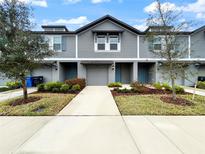 Charming townhome exterior with gray siding, a one-car garage, a well-manicured lawn, and a tidy garden at 2764 Emory Sound Pl, Brandon, FL 33510