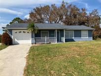 Charming single-story home featuring a blue exterior, well-maintained lawn, and attached one car garage at 12350 Mitchell Ter, Port Charlotte, FL 33981