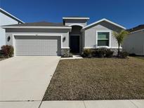 Well-maintained, gray home featuring a two-car garage and beautifully landscaped front yard at 345 Mangrove Manor Dr, Apollo Beach, FL 33572