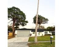 Charming single-story home featuring an attached garage, well-maintained lawn, and mature landscaping at 6391 N 68Th N Ln, Pinellas Park, FL 33781