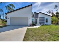 Modern home with a stylish gray and white exterior, two-car garage, and freshly installed landscaping at 4044 Simkins Ave, North Port, FL 34286