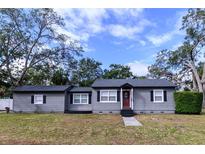 Charming single-story home with a gray exterior, dark trim, manicured lawn, and a vibrant red front door at 3530 Oak Ne St, St Petersburg, FL 33704