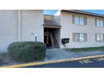 Condo exterior featuring a stucco facade, staircase, and well-maintained landscaping at 7502 Needle Leaf Pl # B66, Tampa, FL 33617