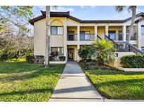 Inviting condo exterior featuring a well-maintained lawn and tropical landscaping at 1801 E Lake Rd # 3A, Palm Harbor, FL 34685