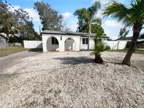 Charming white home with arched entryway, shell driveway, and tropical palm trees at 913 27Th E St, Bradenton, FL 34208