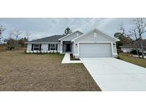 New construction home with gray exterior, two-car garage, and landscaped yard at 13106 Nusser Ave, Weeki Wachee, FL 34614