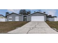 Gray house with white garage door and landscaping at 12117 Topaz St, Spring Hill, FL 34608