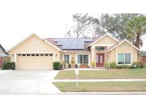 House exterior featuring solar panels, two-car garage, and landscaped lawn at 812 Walsingham Way, Valrico, FL 33594