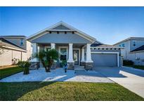 One-story home with gray siding, two-car garage, and landscaped front yard at 1280 Windy Bay Shl, Tarpon Springs, FL 34689