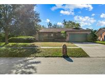 Brick house with a green garage door and well-maintained lawn at 1813 Laurel Oak Dr, Valrico, FL 33596