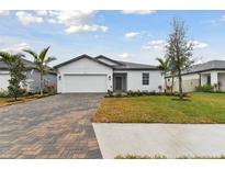 One-story home with a white exterior, gray roof, and brick paver driveway at 5213 Patano Loop, Palmetto, FL 34221