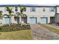 Three-unit townhome building with light blue garage doors and landscaping at 5414 Tripoli Dr, Palmetto, FL 34221