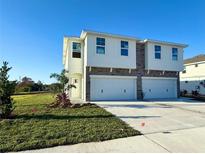 Two-story house with a two-car garage, stone accents, and a neatly landscaped lawn at 13719 Emerald Fields Dr, Hudson, FL 34667