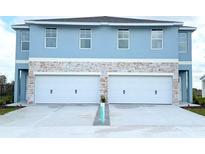 Two-story duplex with attached garages and light blue exterior at 13998 Emerald Fields Dr, Hudson, FL 34667