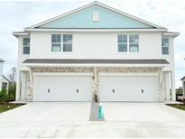 Two-story duplex with light blue accents, two-car garage, and driveway at 14024 Emerald Fields Dr, Hudson, FL 34667