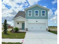 Two-story house with light teal and white siding, three-car garage, and landscaping at 7950 Chandler Lake Ct, Hudson, FL 34667