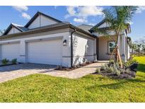 Beautiful home with a two car garage, manicured lawn and brick walkway at 18024 Cherished Loop, Bradenton, FL 34211
