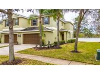 Two-story townhome with brown garage doors and a well-manicured lawn at 8609 Fiddleleaf Ct, Tampa, FL 33647