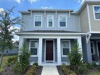 Two-story townhome with gray siding, white trim, and a dark brown door at 5046 Avalon Park Blvd, Wesley Chapel, FL 33545