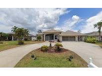 House exterior features a large driveway and manicured lawn at 13 Pebble Beach Rd, Rotonda West, FL 33947