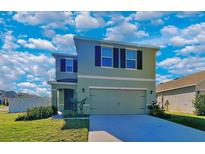 Two-story house with two-car garage, landscaped lawn, and a light-green exterior at 5125 Old Turner Ln, Palmetto, FL 34221