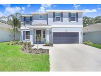 Charming two-story home featuring a two-car garage, landscaped yard, and stylish blue exterior with coordinating shutters at 2437 Orange Harvest Pl, Seffner, FL 33584