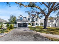 Two-story modern home with white brick exterior, black garage doors, and a paved driveway at 2106 S Cortez Ave, Tampa, FL 33629