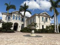 Stately cream-colored home featuring a beautiful brick circular driveway and a tranquil stone fountain at 19451 Ganton Ave, Bradenton, FL 34202