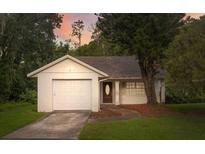 One story house with attached garage, landscaped yard, and a walkway to the front door at 7613 Piping Rock Ct, New Port Richey, FL 34654
