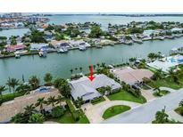 Aerial view of waterfront home with private dock and lush landscaping at 221 Howard Dr, Belleair Beach, FL 33786