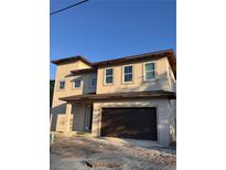 A two-story stucco house with a dark garage door and several rectangular windows on the second floor at 4021 W Santiago St, Tampa, FL 33629