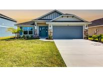 Two-story house with gray garage door and teal front door, stone accents, and landscaping at 6818 162Nd E Pl, Parrish, FL 34219