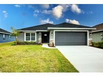 New single-story home with gray exterior, two-car garage, and landscaped lawn at 6830 162Nd Place E. E Pl, Parrish, FL 34219