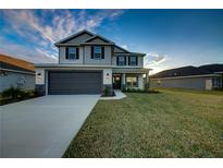 Two-story house with gray siding, dark garage door, and landscaped lawn at 16131 69Th Lane East, Parrish, FL 34219