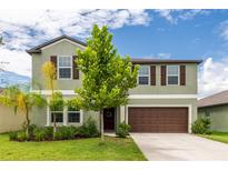 Two-story house with green exterior, brown accents, and a well-manicured lawn at 5429 Blue Azure Dr, Wimauma, FL 33598