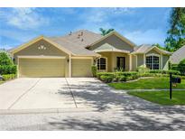 Tan three-car garage house with manicured lawn at 806 Red Ash Ct, Seffner, FL 33584