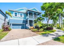 Two-story blue home with a two-car garage, front porch and tropical landscaping at 905 Seagrape Dr, Ruskin, FL 33570