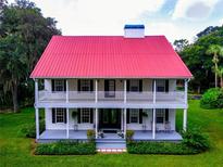 Two-story house with red metal roof, wrap-around porch, and landscaped lawn at 4502 Hill Dr, Valrico, FL 33596