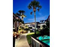 Night view of condo building with lush landscaping, walkways, and a pond at 3035 Countryside Blvd # 14B, Clearwater, FL 33761